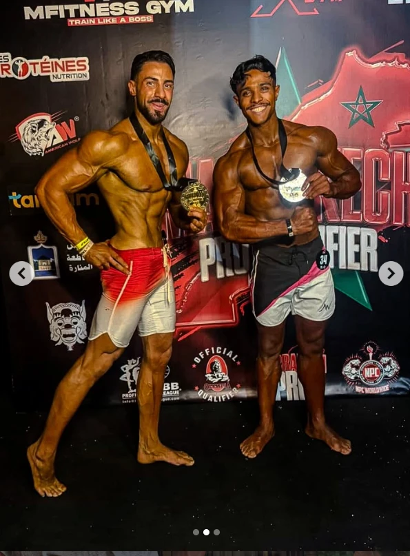 Mohamed Ahizoune holding his medal alongside another competitor on the podium